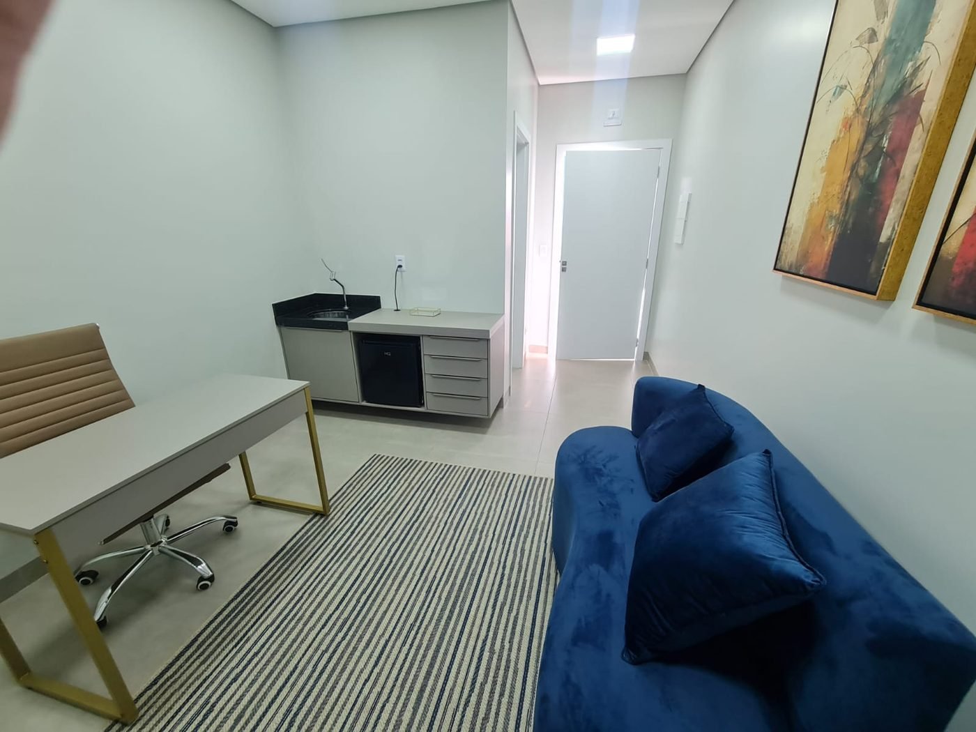 Consultório médico com mesa, sofá e pia de apoio