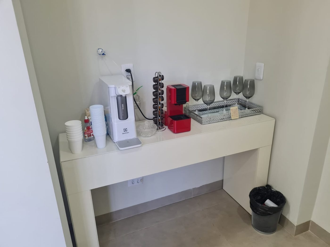 Bancada de cortesia com café, água e taças à disposição dos pacientes